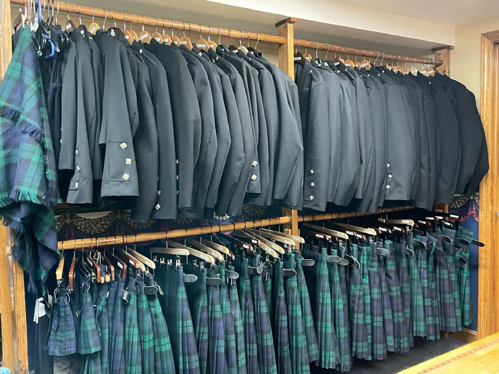 Highland jackets and Black Watch tartan kilts displayed on rental racks at Celtic Crossing.